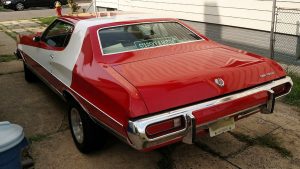 A classic Ford Torino painted red with a white stripe like in Starsky and Hutch.