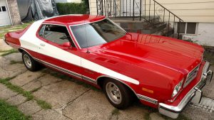 A classic Ford Torino painted red with a white stripe like in Starsky and Hutch.